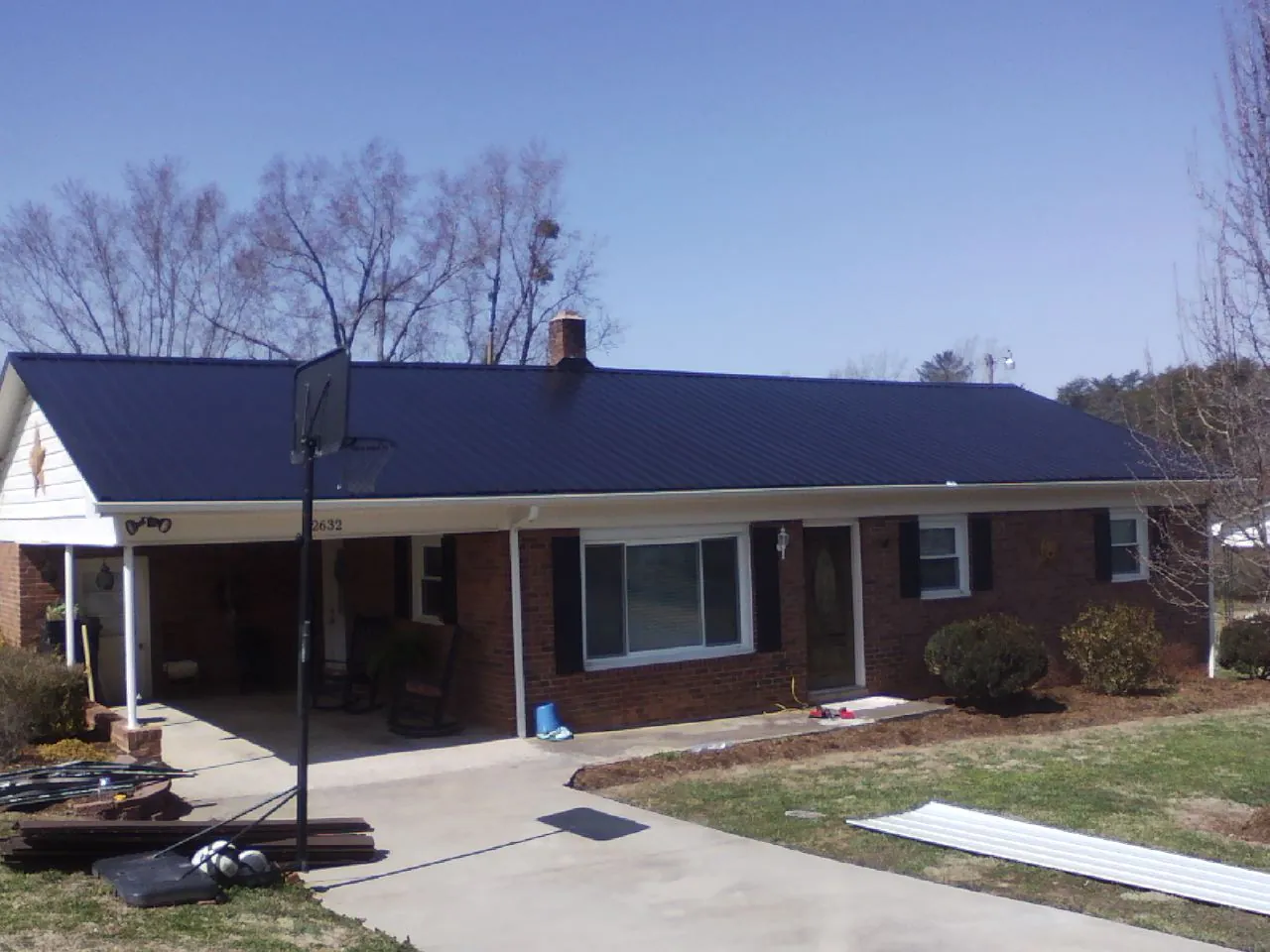 Finished dark blue metal roof on a brick ranch with a carport in Albert Lea