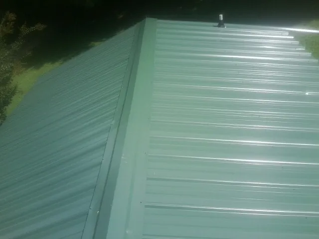 New green metal panels meeting at the ridge of a roof — Flat Roof Repair work by our crew in Albert Lea