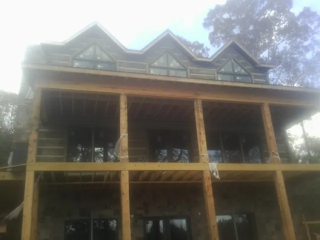 Dormers and porch framing on a large log home under construction — Roof Coating work by our crew in Albert Lea
