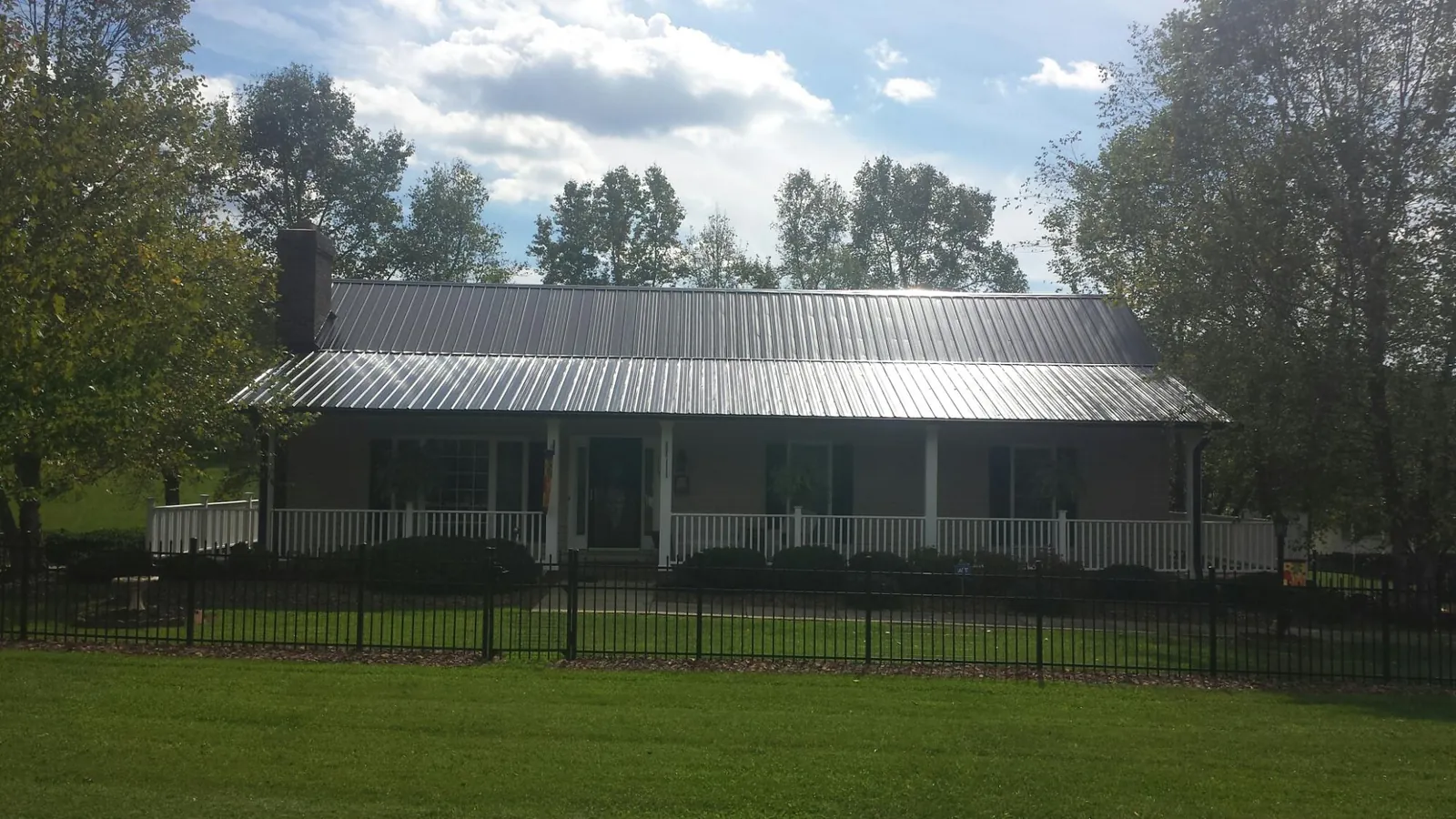 Gray metal roof on a brick ranch with a full width front porch — Gutter Guard Installation work by our crew in Albert Lea