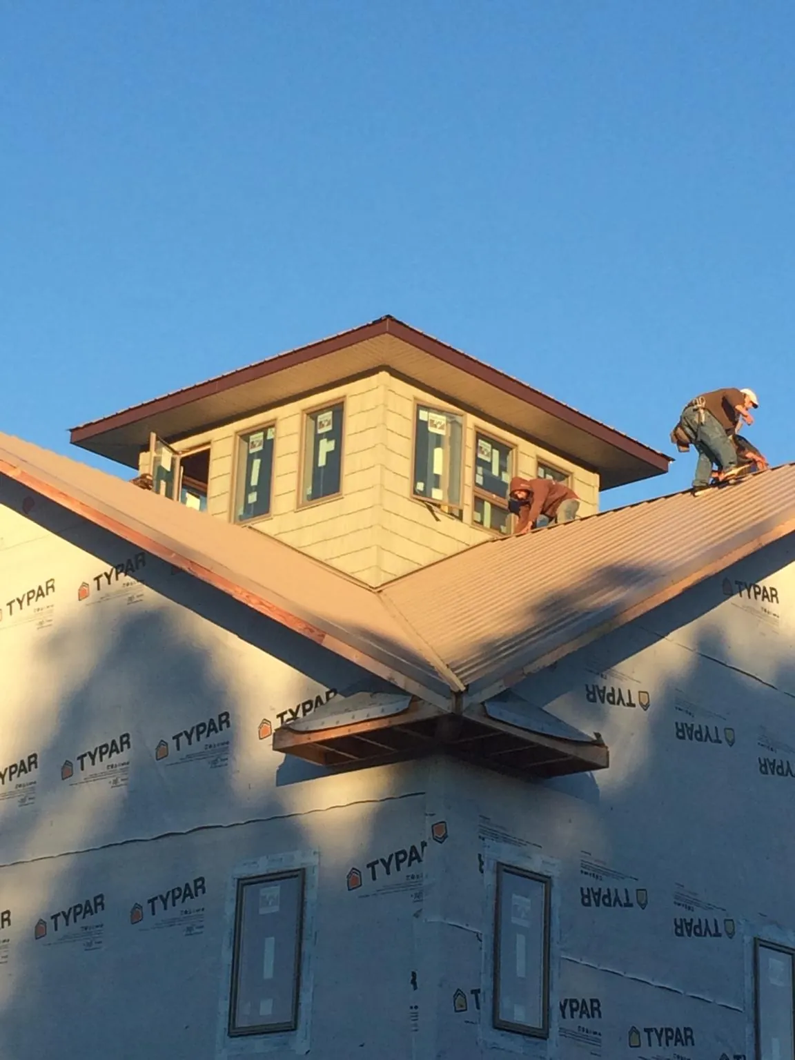 Roofers working around a rooftop cupola on a new metal roof at sunset — Roof Waterproofing in Albert Lea by Roofing Brothers